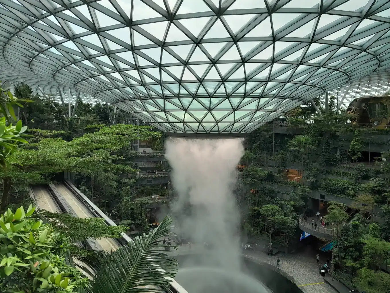 Indoor waterfall surrounded by lush greenery.