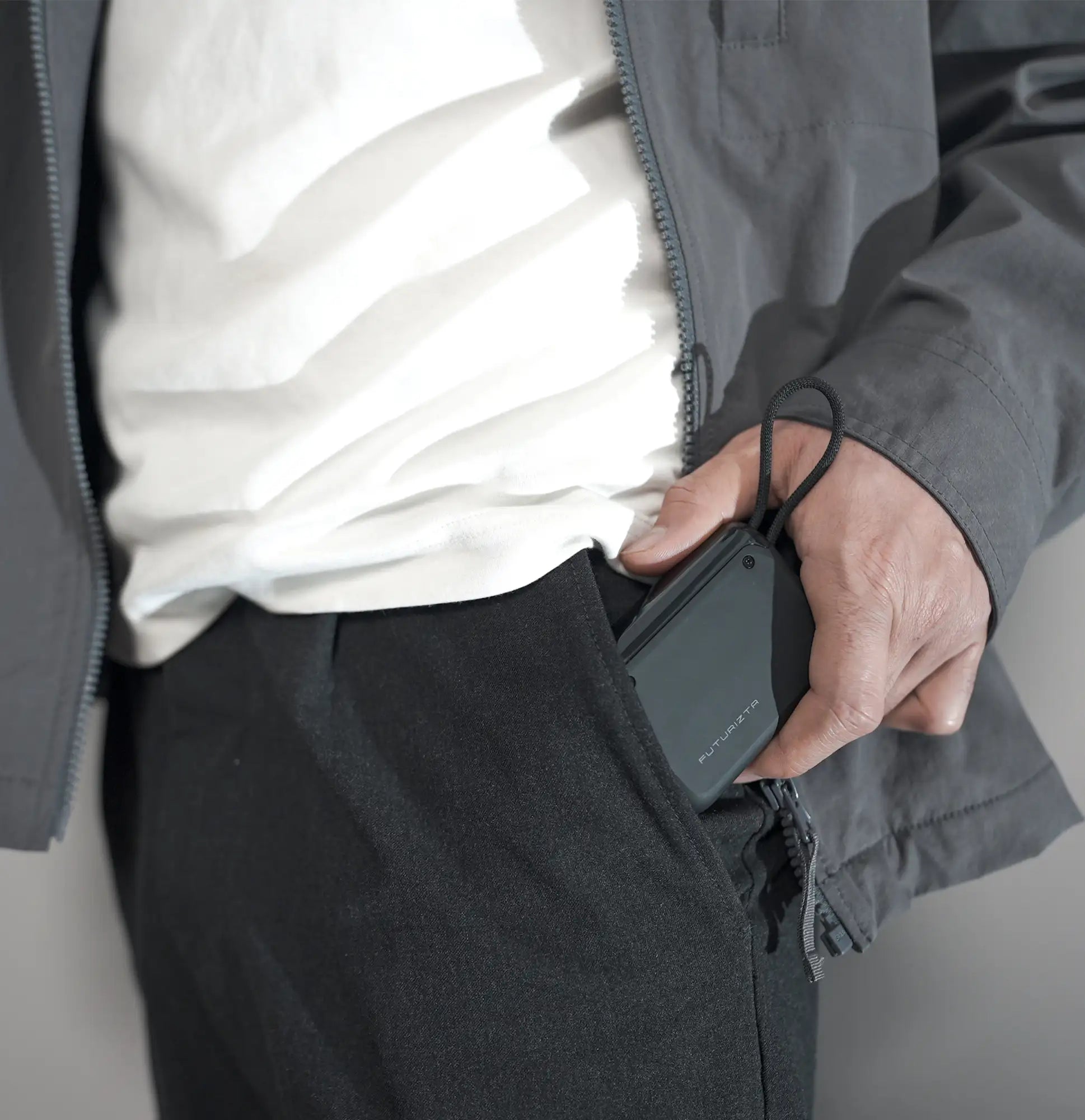 Black rectangular portable charger with a textured surface and a braided cord attached.