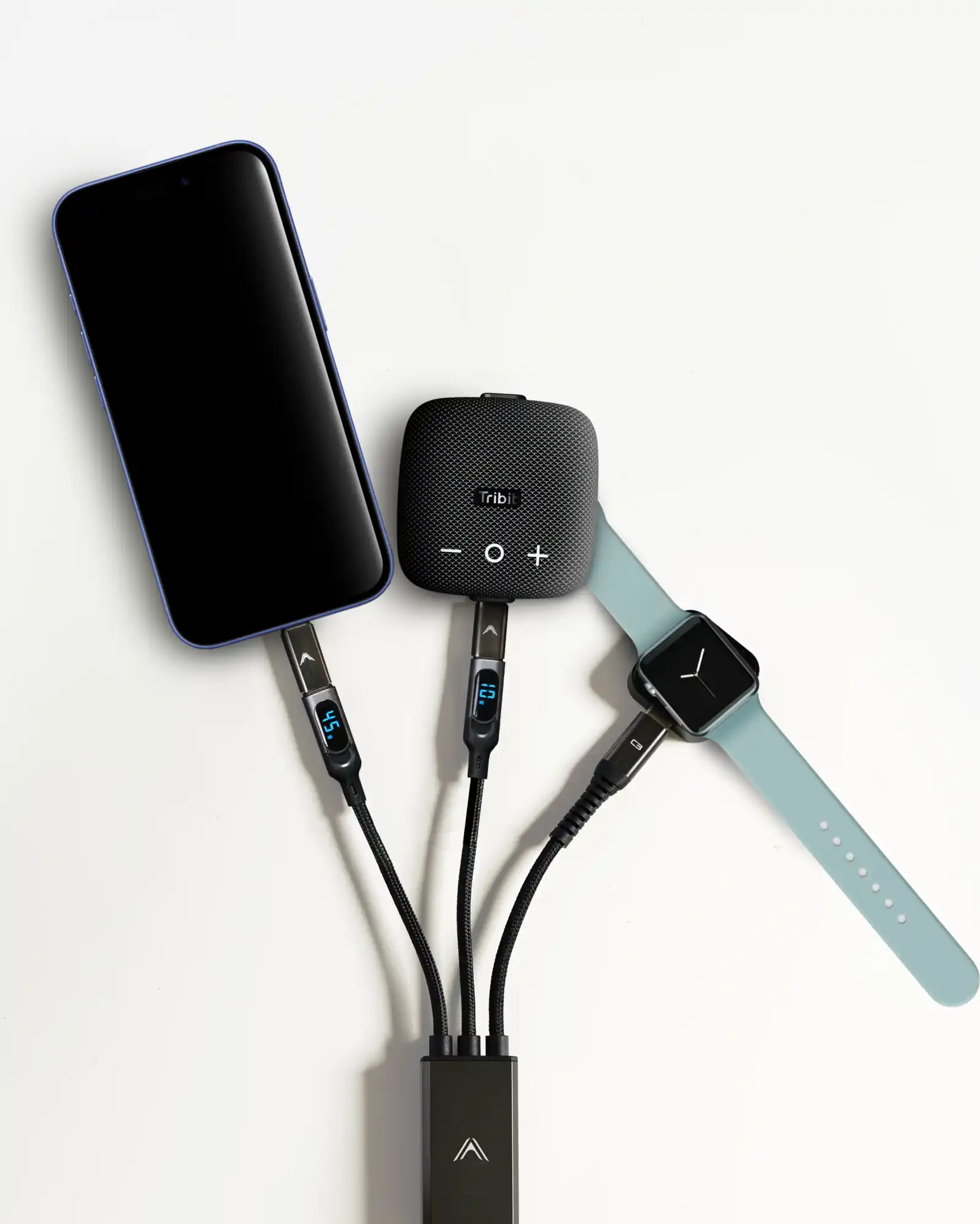 A multi-device charging station with cables connected to a phone, a portable speaker, and a smartwatch.